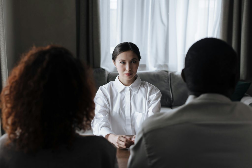 A social worker talks to a diverse couple in a home setting.